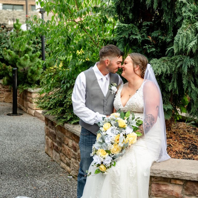 Bride with a yellow and white bouquet and groom posing in the garden courtyard at Wyndham Garden York