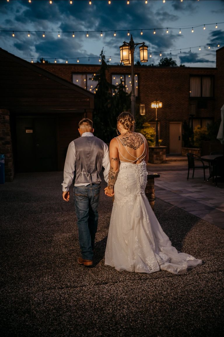 Bride and groom walking through the courtyard under string lights at night at Wyndham Garden York