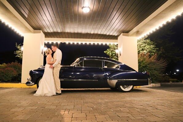 Bride and groom kissing beside a vintage car under the lit porte cochère at Wyndham Garden York